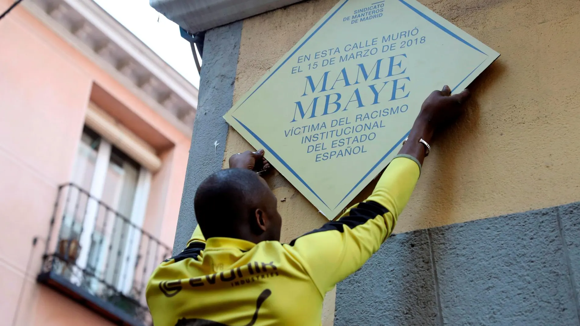 Un hombre coloca un placa durante la concentración convocada por el Sindicato de Manteros esta tarde en la plaza de Nelson Mandela, en Madrid, en recuerdo a Mame Mbaye