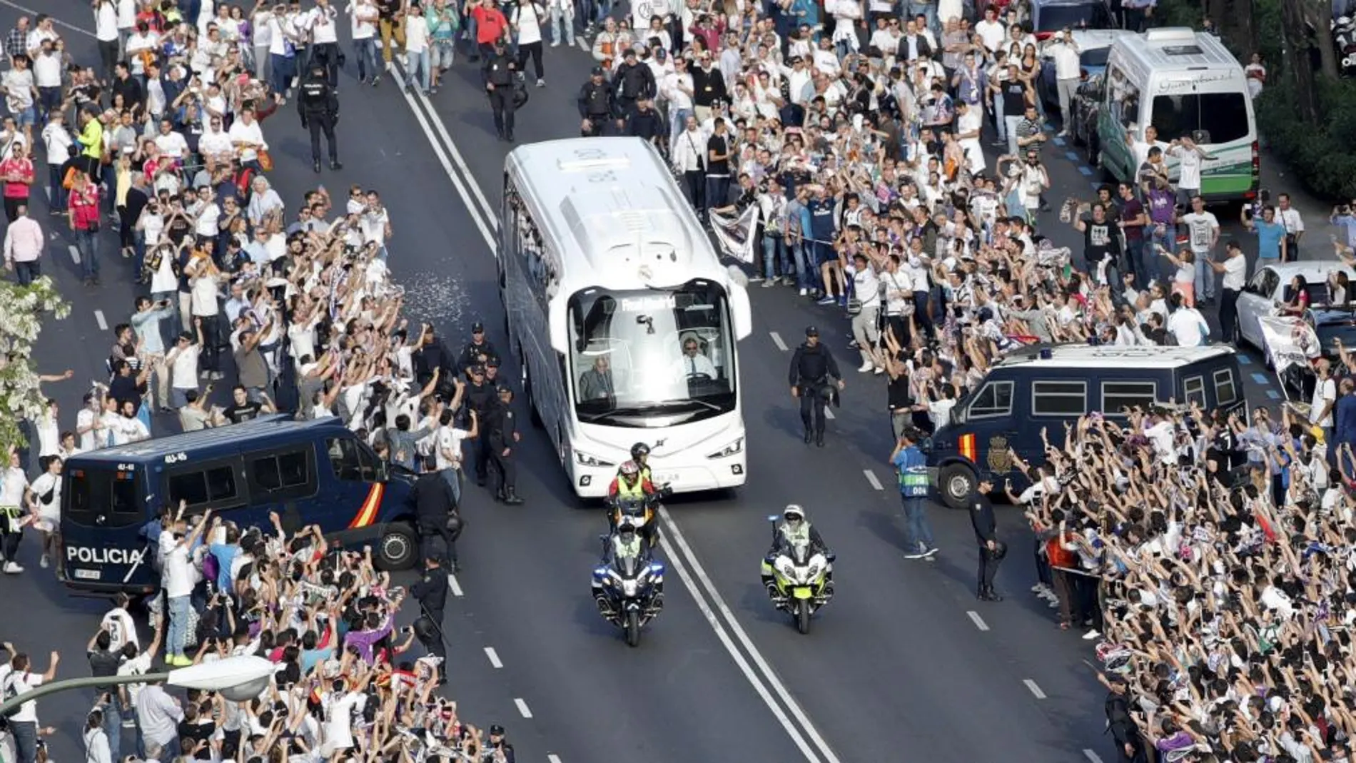 Aficionados del Real Madrid reciben el autobús que traslada a los jugadores al estadio Santiago Bernabéu.