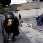 Varios manifestantes se protegen de los ataques de la Guardia Nacional durante una manifestación en Caracas