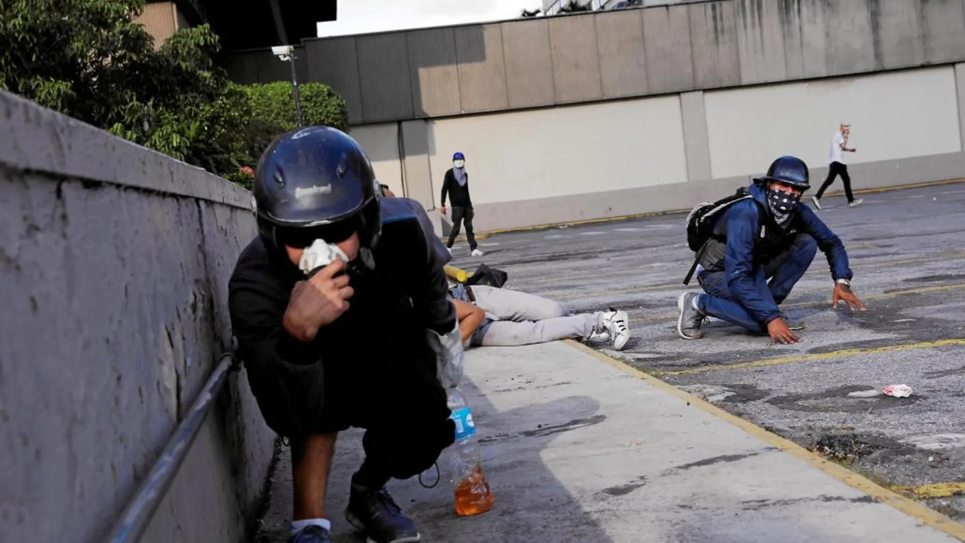 Varios manifestantes se protegen de los ataques de la Guardia Nacional durante una manifestación en Caracas