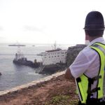 Un policía observa el estado en que se encuentra el buque "Fedra"que el pasado viernes encalló debido al fuerte temporal de lluvia y viento registrado en el Estrecho de Gibraltar, y el sábado se partió en dos vertiendo al mar 150 de las 300 toneladas que albergaba en uno de sus tanques para su propio abastecimiento.