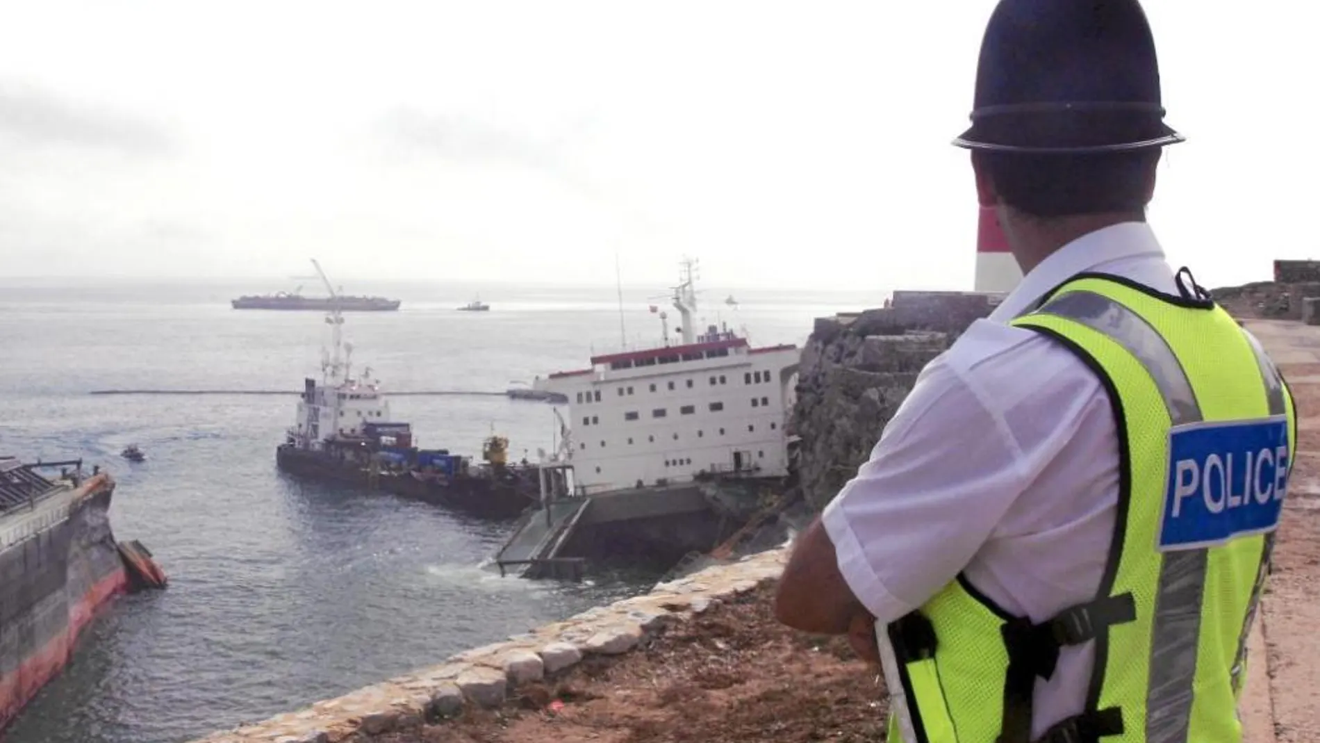 Un policía observa el estado en que se encuentra el buque "Fedra"que el pasado viernes encalló debido al fuerte temporal de lluvia y viento registrado en el Estrecho de Gibraltar, y el sábado se partió en dos vertiendo al mar 150 de las 300 toneladas que albergaba en uno de sus tanques para su propio abastecimiento.