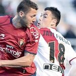 El centrocampista del Osasuna David Timor (i) disputa un balón con el centrocampista del Rayo Vallecano Javi Fuego