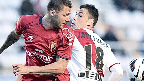 El centrocampista del Osasuna David Timor (i) disputa un balón con el centrocampista del Rayo Vallecano Javi Fuego