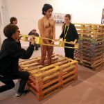Enjaulado. Cada día, el artista Emilio Rojas se introduce en una «cárcel» de palés completamente desnudo y ayudado por el personal de la galería José de la Fuente