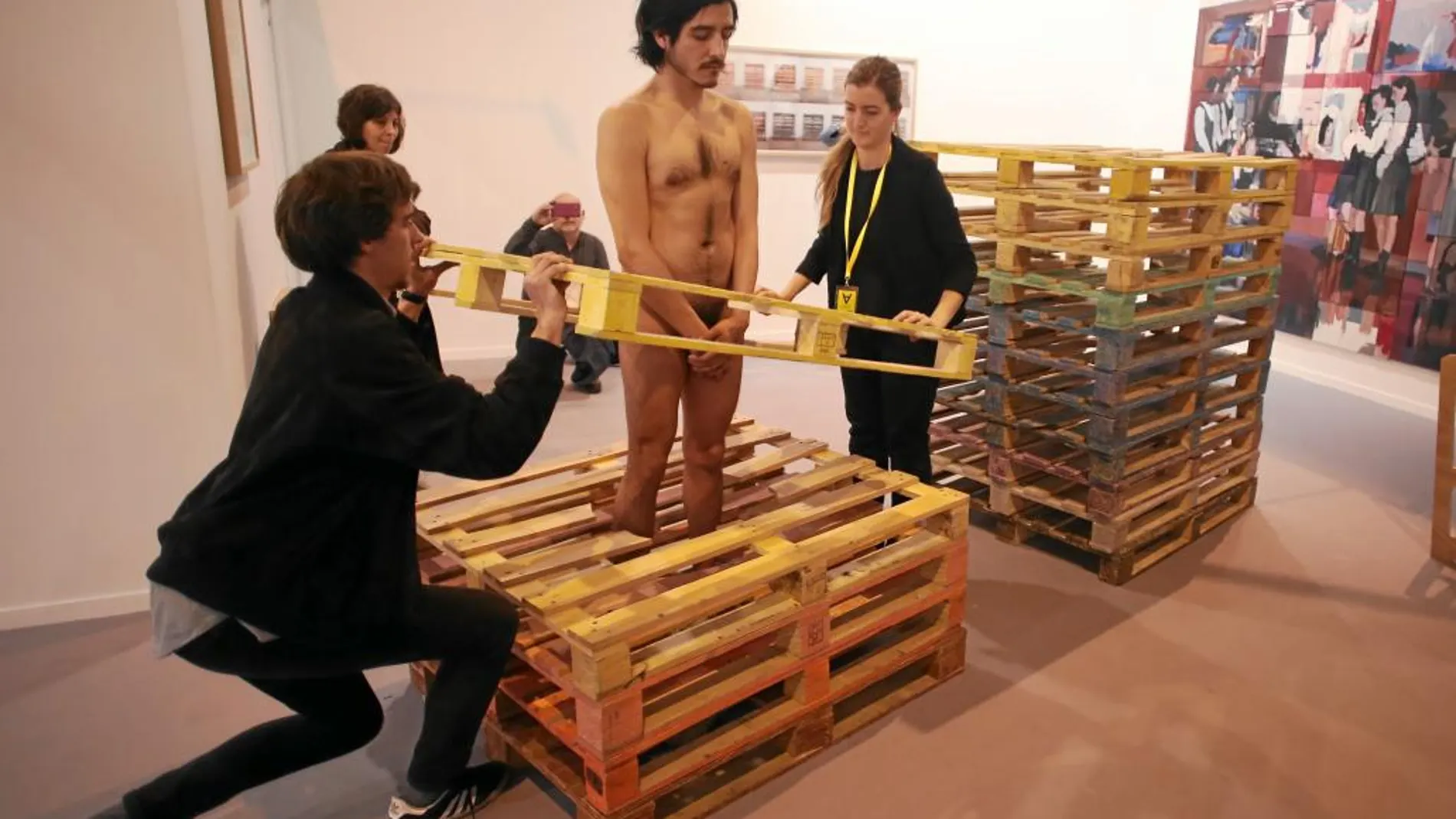 Enjaulado. Cada día, el artista Emilio Rojas se introduce en una «cárcel» de palés completamente desnudo y ayudado por el personal de la galería José de la Fuente