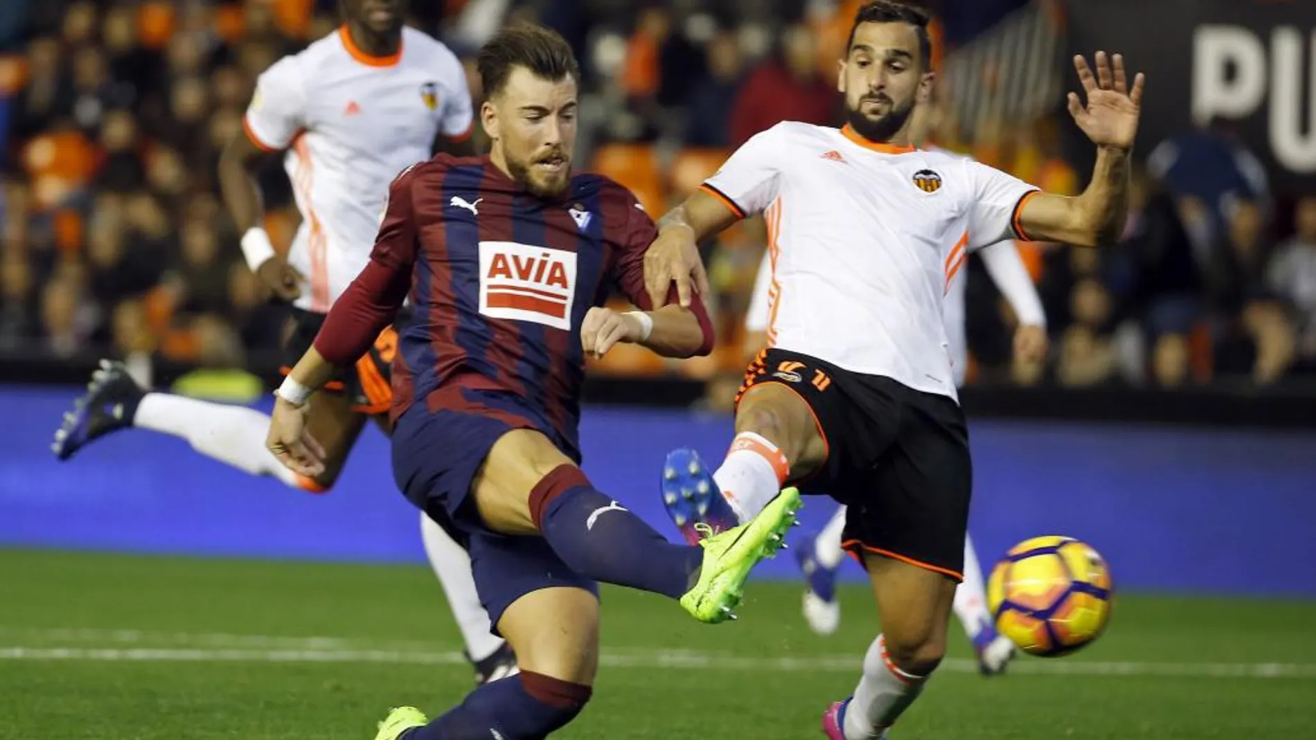 El jugador del Eibar, Sergi Enrich (i), chuta a portería en presencia del del Valencia, Martin Montoya