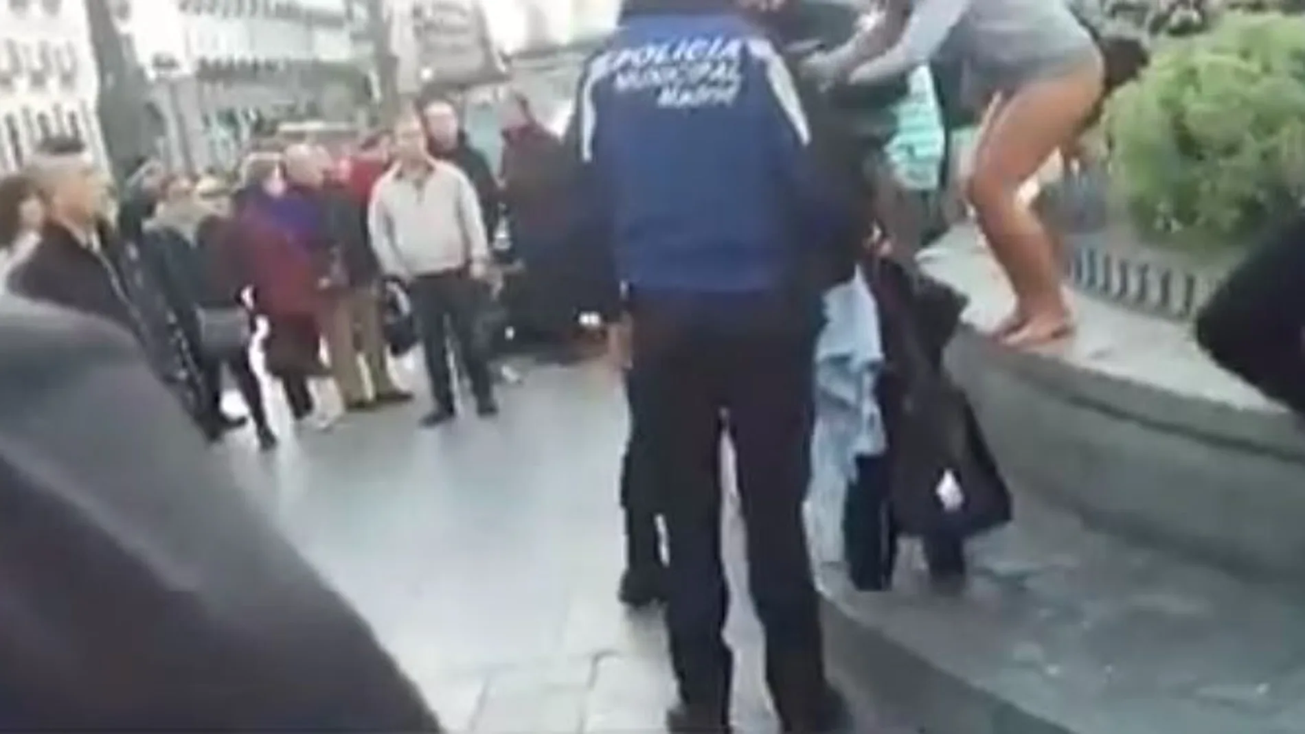 Captura del vídeo divulgado por Telemadrid en el que se puede ver a la mujer saliendo de la fuente en presencia de agentes municipales