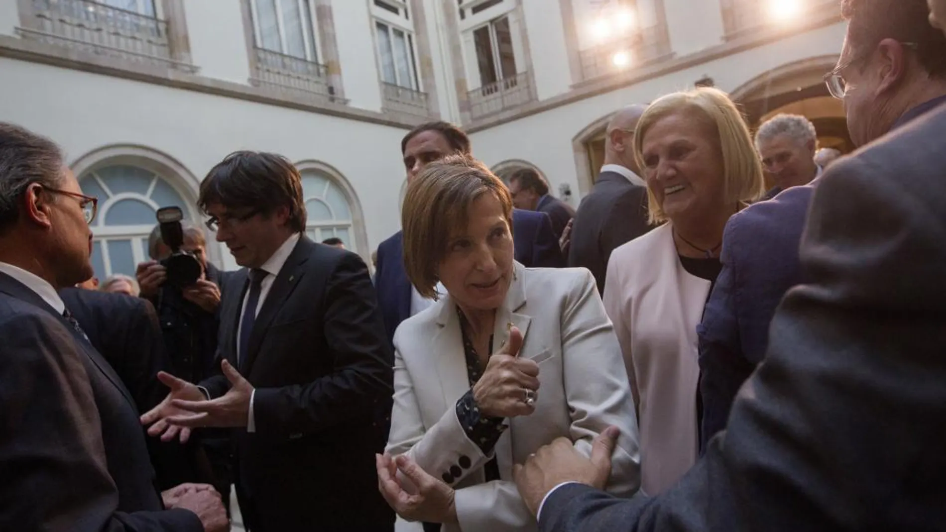 Carme Forcadell (c), junto al presidente catalán, Carles Puigdemont (i), se despide de Francesc Homs (d), durante un acto de apoyo a ella el pasado 19 de abril