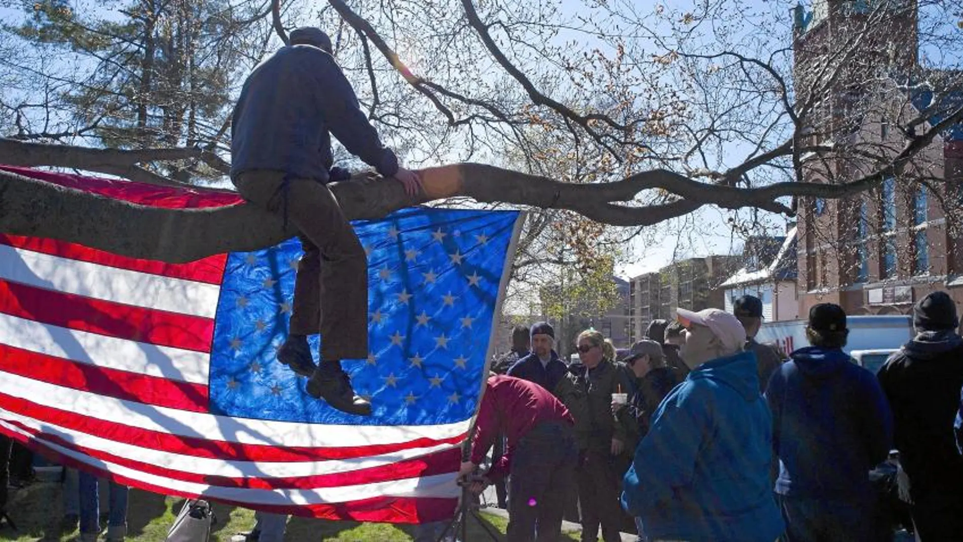 Un hombre sentado sobre la rama de un árbol contempla la iglesia de San José, donde se celebró ayer el funeral por una de las víctimas del atentado de Boston