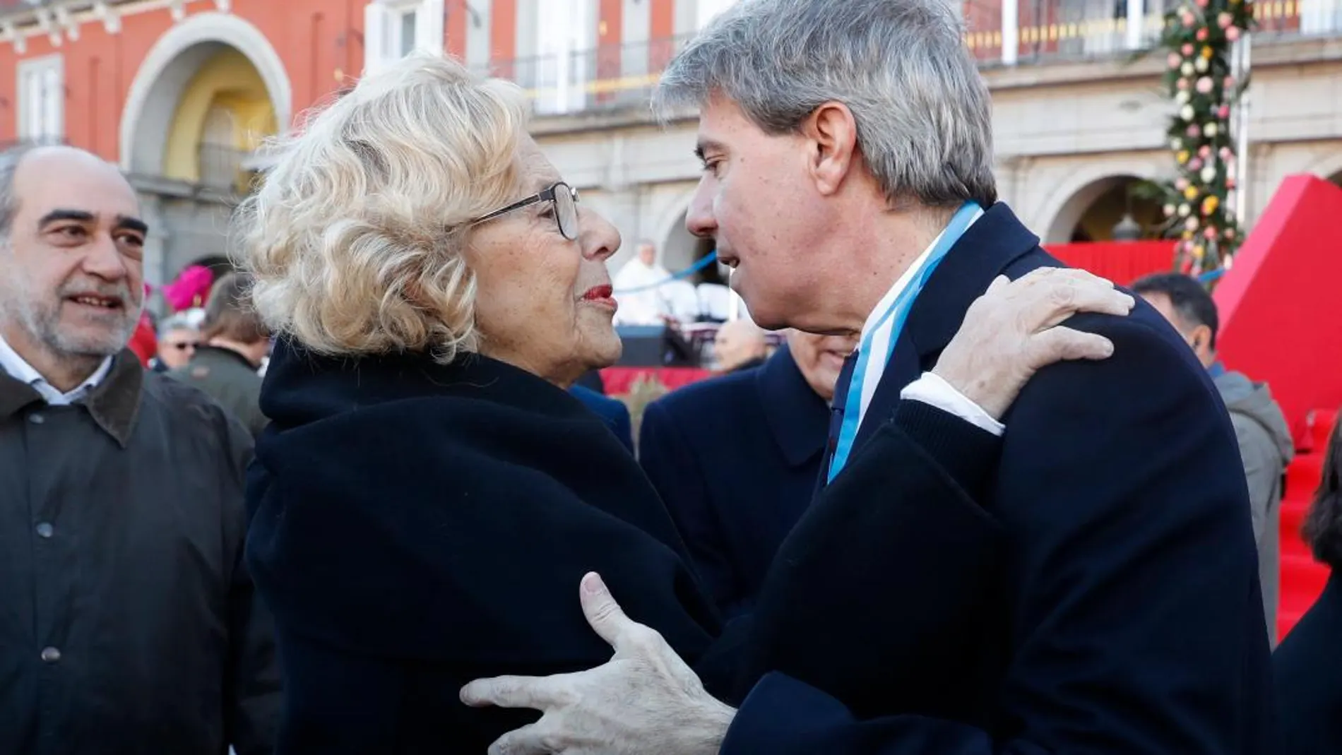 La alcaldesa de Madrid, Manuela Carmena, saluda al presidente madrileño, Ángel Garrido, a su llegada a la plaza Mayor de Madrid para asistir a la tradicional misa en honor a la Virgen de La Almudena