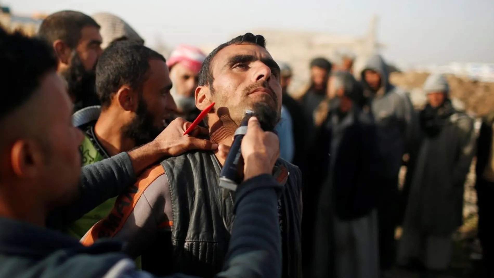 Imagen de un hombre afeitando a uno de los ocupantes del campamento instalado en Hamam al-Alil, al sur de Mosul