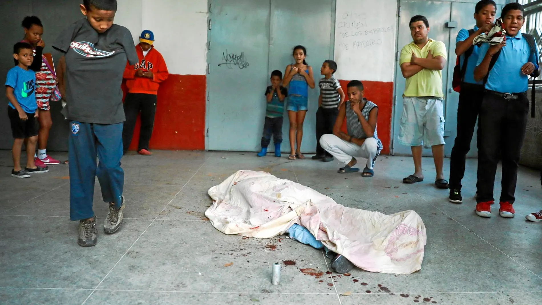 Varias personas observan el cadáver de una persona muerta por una bala durante las protestas en Caracas, ayer