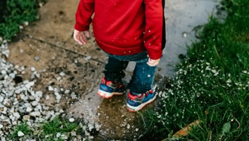 Niño se divierte saltando en un charco | Fuente: Pexels