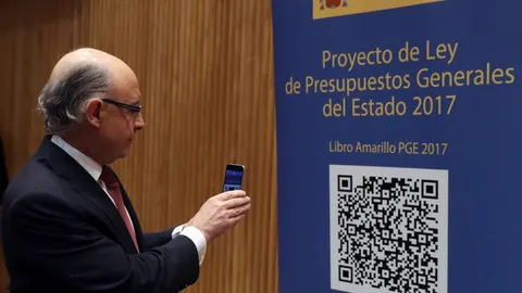 El ministro de Hacienda, Cristóbal Montoro, escanea con el móvl el código QR del proyecto de Ley de Presupuestos Generales del Estado (PGE) para 2017.