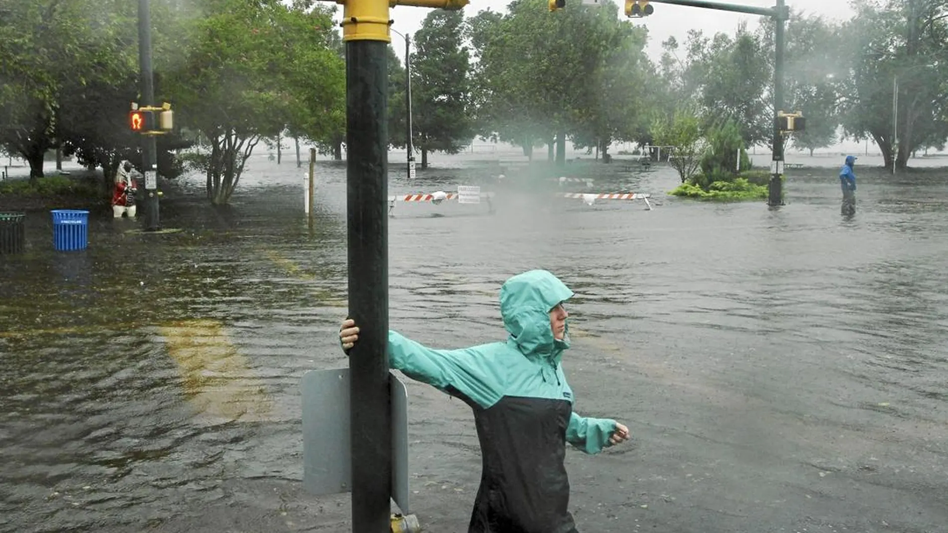 Una mujer trata de atravesar una carretera inundada en el parque «Union Point» de New Bern en Carolina del Norte, ayer