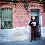 El historiador Ian Gibson, ayer, ante la famosa fachada que fotografió Robert Capa, con un libro del fotógrafo