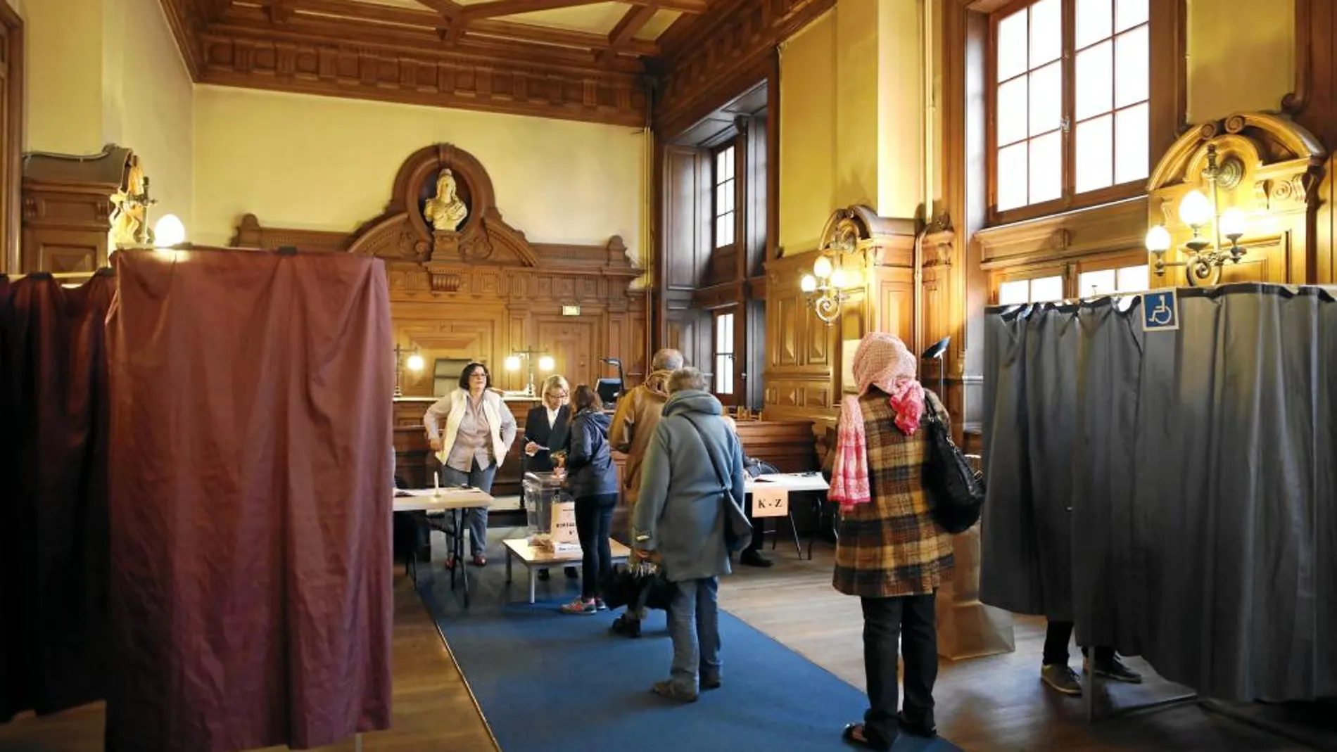 Ciudadanos franceses hacen cola para ejercer su derecho de voto ayer en un centro electoral en París