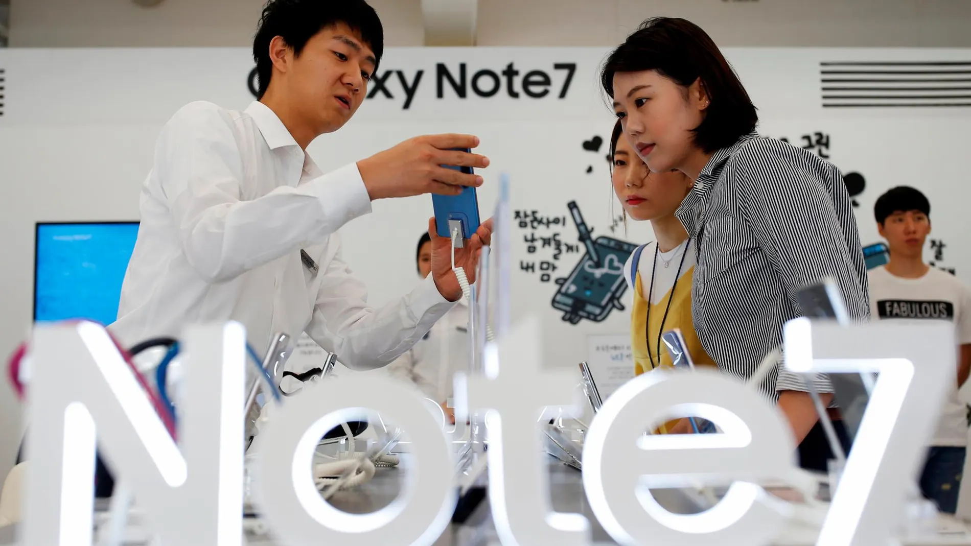 Dos clientas y un vendedor en una tienda de móviles Samsung en Corea del Sur / Reuters