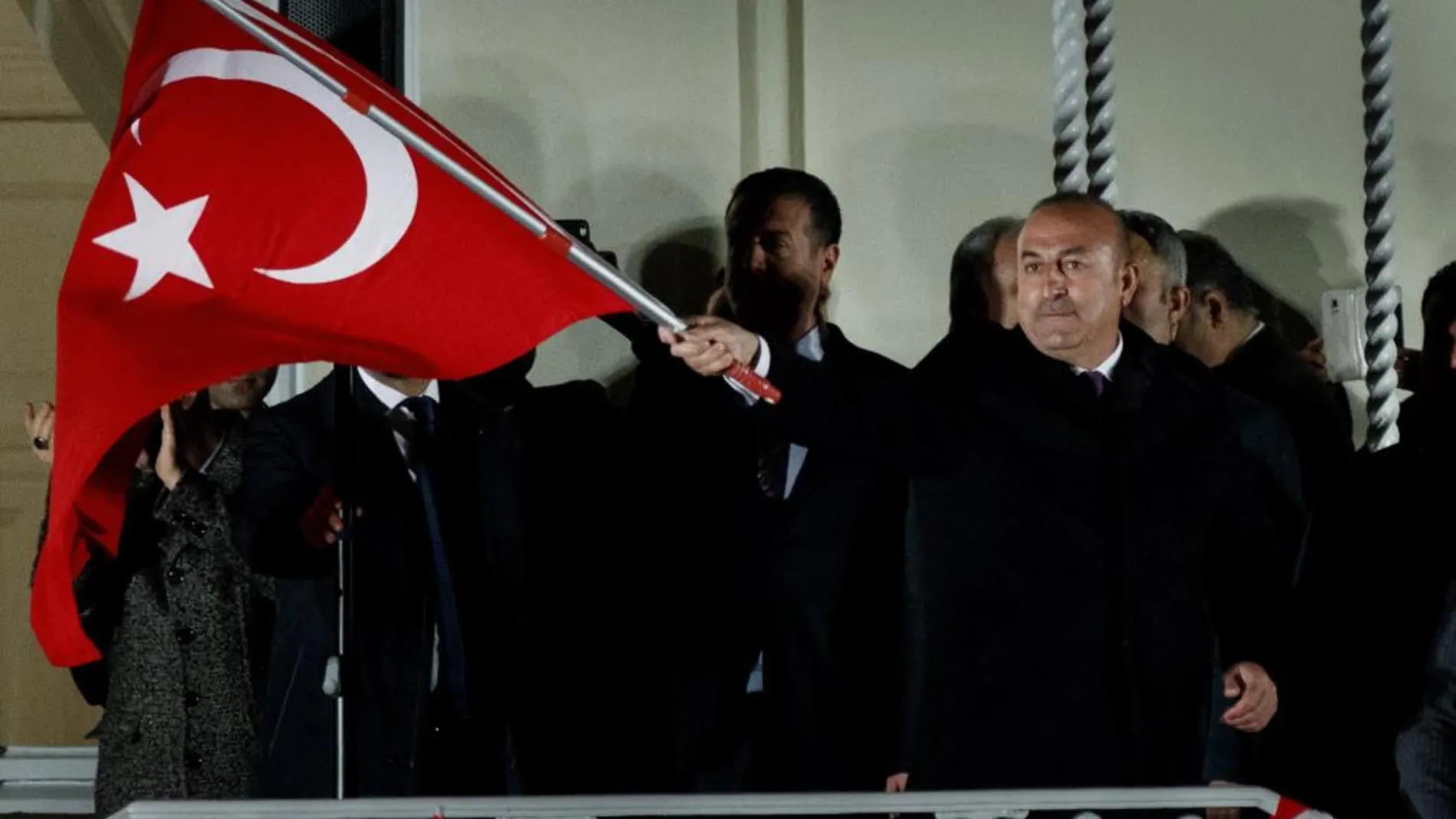 El ministro de Exteriores turco, Mevlut Cavusoglu (C), ondea la bandera turca ante seguidores del Gobierno de ese país, en los jardines del Consulado de Turquía en Hamburgo