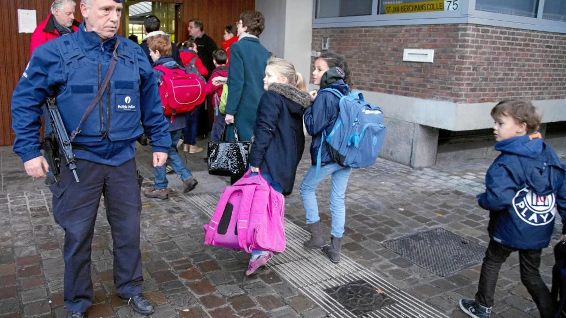 Niños frente a un policía a la entrada de una escuela en Bruselas