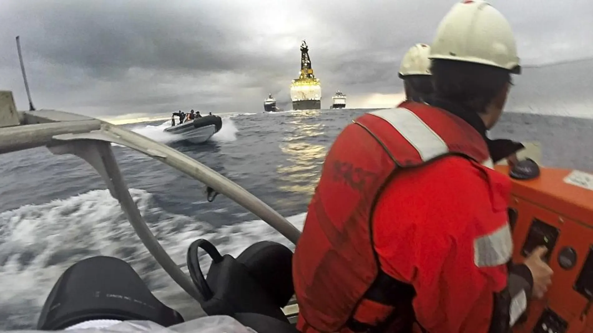 Fotografía facilitada por Greenpeace de dos activistas en una de sus lanchas y otra de la Armada española durante la protesta frente a la plataforma Rowan Renaissance contra las prospecciones petrolíferas.