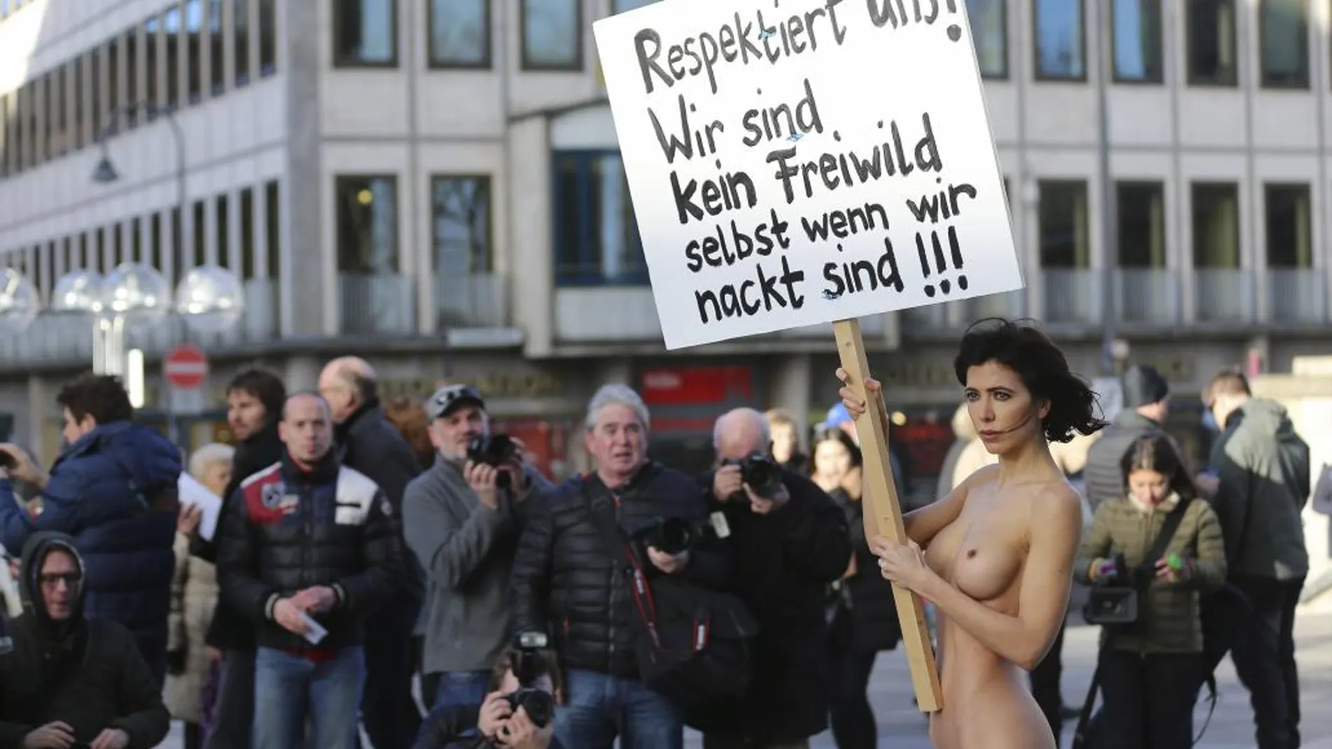 La artista sueca Milo Moire se manifiesta sin ropa mientras sostiene un cartel que reza "¡Respétanos! ¡No somos carne de presa ni aunque estemos desnudas!"en la plaza central de Colonia (Alemania).