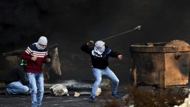 AVarias palestinos lanzan piedras contra el ejército israelí en el asentamiento de Beit El, cerca de Ramala