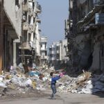 Un niño juega entre edificios destrozados en la ciudad de Homs