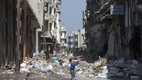 Un niño juega entre edificios destrozados en la ciudad de Homs