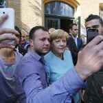 Angela Merkel, con tres refugiados en un centro de Berlín