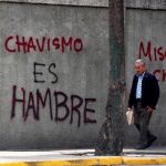 Un hombre camina por las calles de Caracas frente a una pintada en contra del chavismo, en 2017