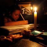 Una niña trabaja durante un corte eléctrico en una foto de archivo