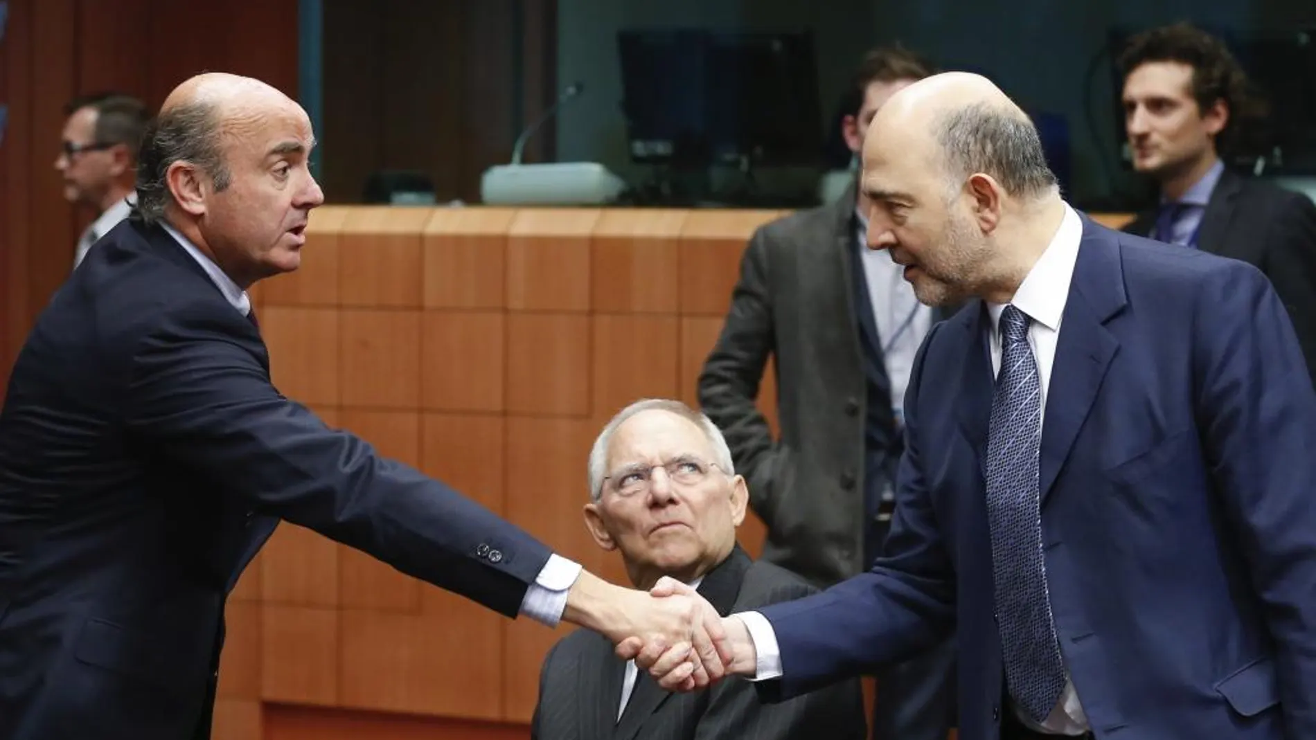 Luis de Guindos estrecha la mano de Pierre Moscovici en la cumbre de ministros de Economía de la zona del euro, el pasado febrero.
