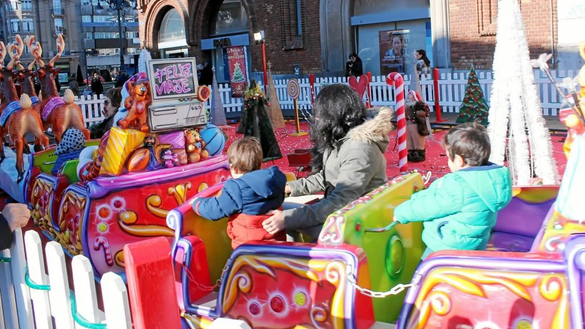 Una familia se monta en una de las atracciones navideñas de León adscritas a la iniciativa «Un kilo, un viaje»