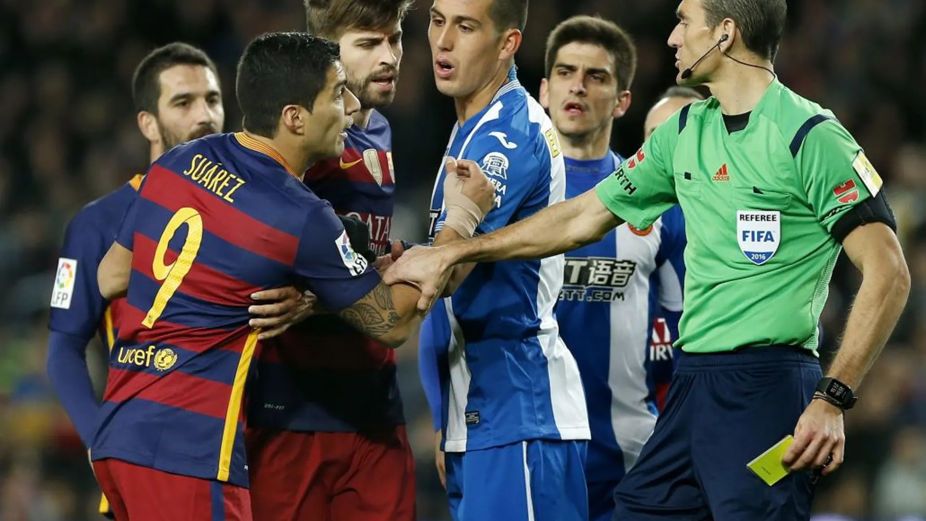 El árbitro Juan Martínez Munuera (d) muestra la tarjeta amarilla al delantero uruguayo del FC Barcelona Luis Suárez (i), durante el partido
