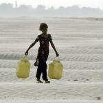 Una niña acarrea dos bidones para recoger agua en una seca región de India