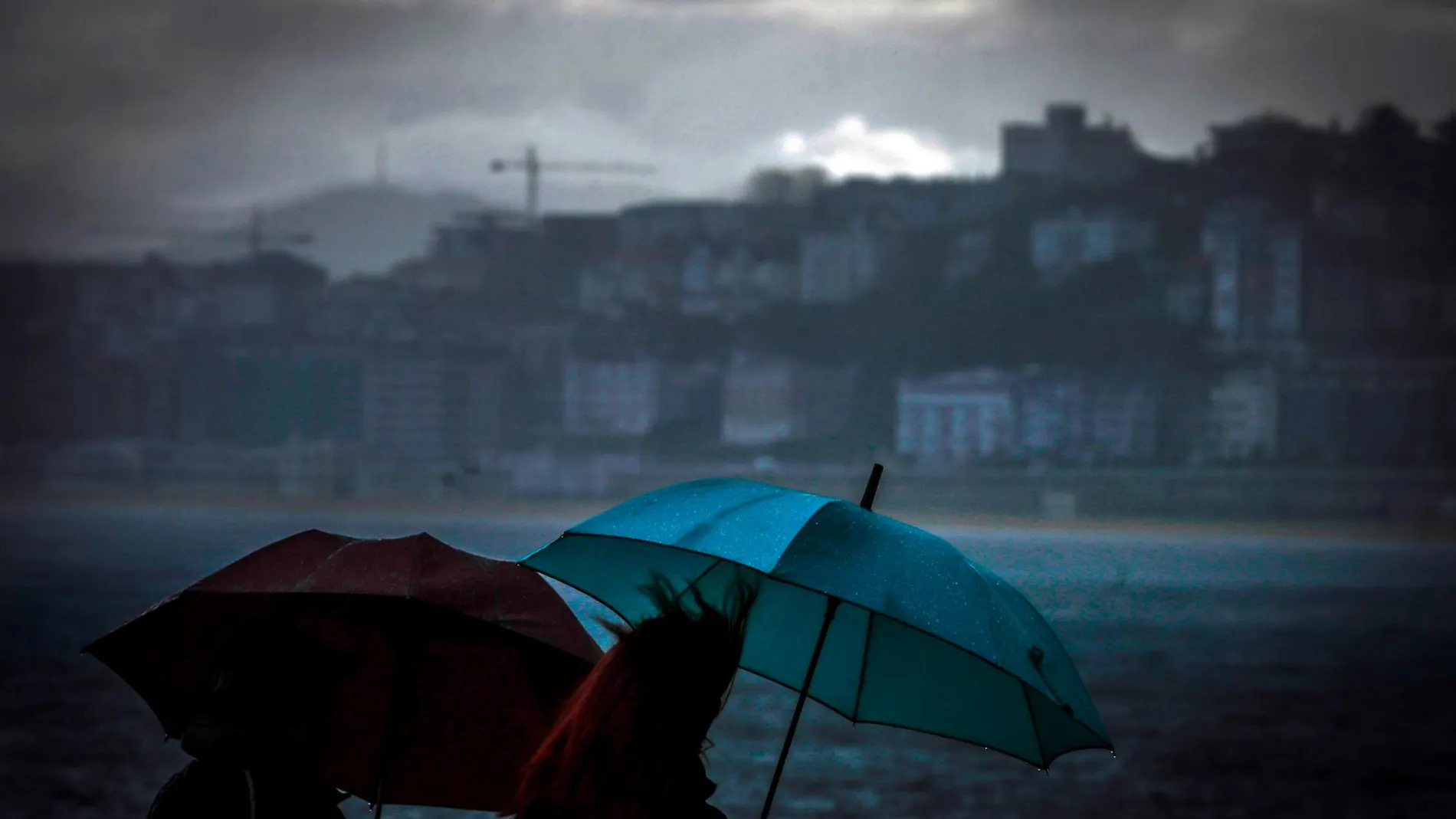 Dos mujeres caminan bajo la lluvia junto a la playa de Ondarreta de San Sebastián | Efe