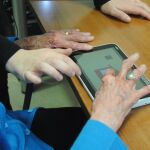 Una mujer interactúa con una tablet en un programa de La Caixa para frenar la demencia