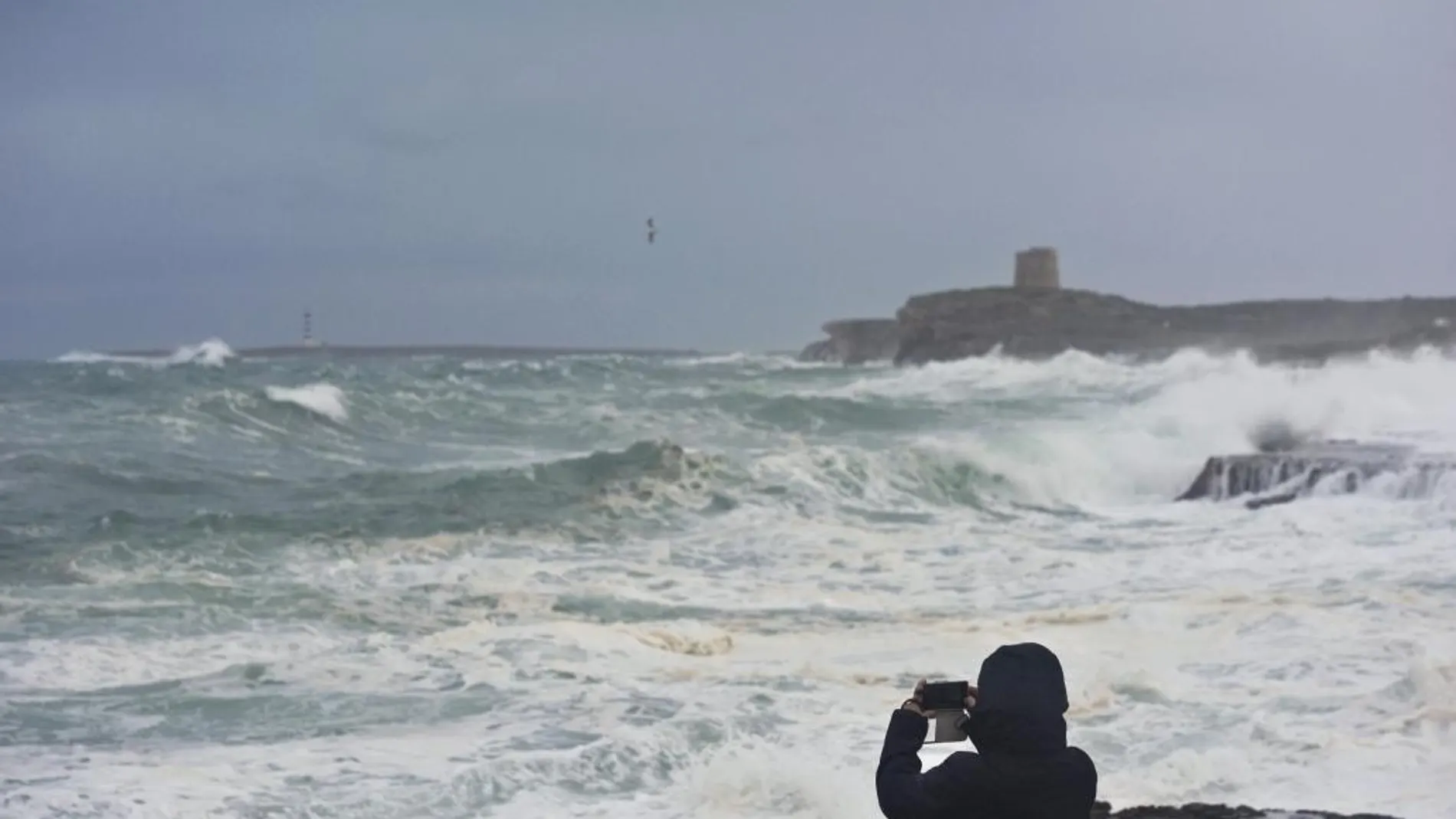 Una persona fotografía la torre de Alcalfar desde S'Algar en el municipio de Sant LLuís, Menorca