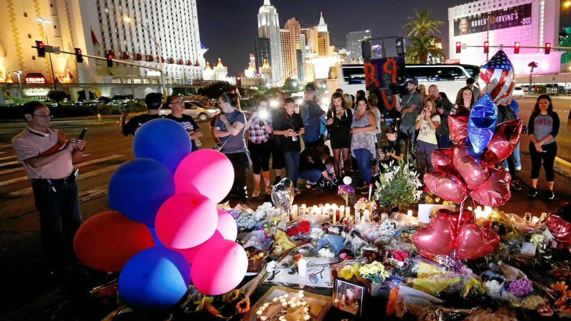 Un grupo de personas se reúne en un homenaje a las víctimas improvisado en una avenida de Las Vegas. A la izquierda, el autor de la masacre y su novia