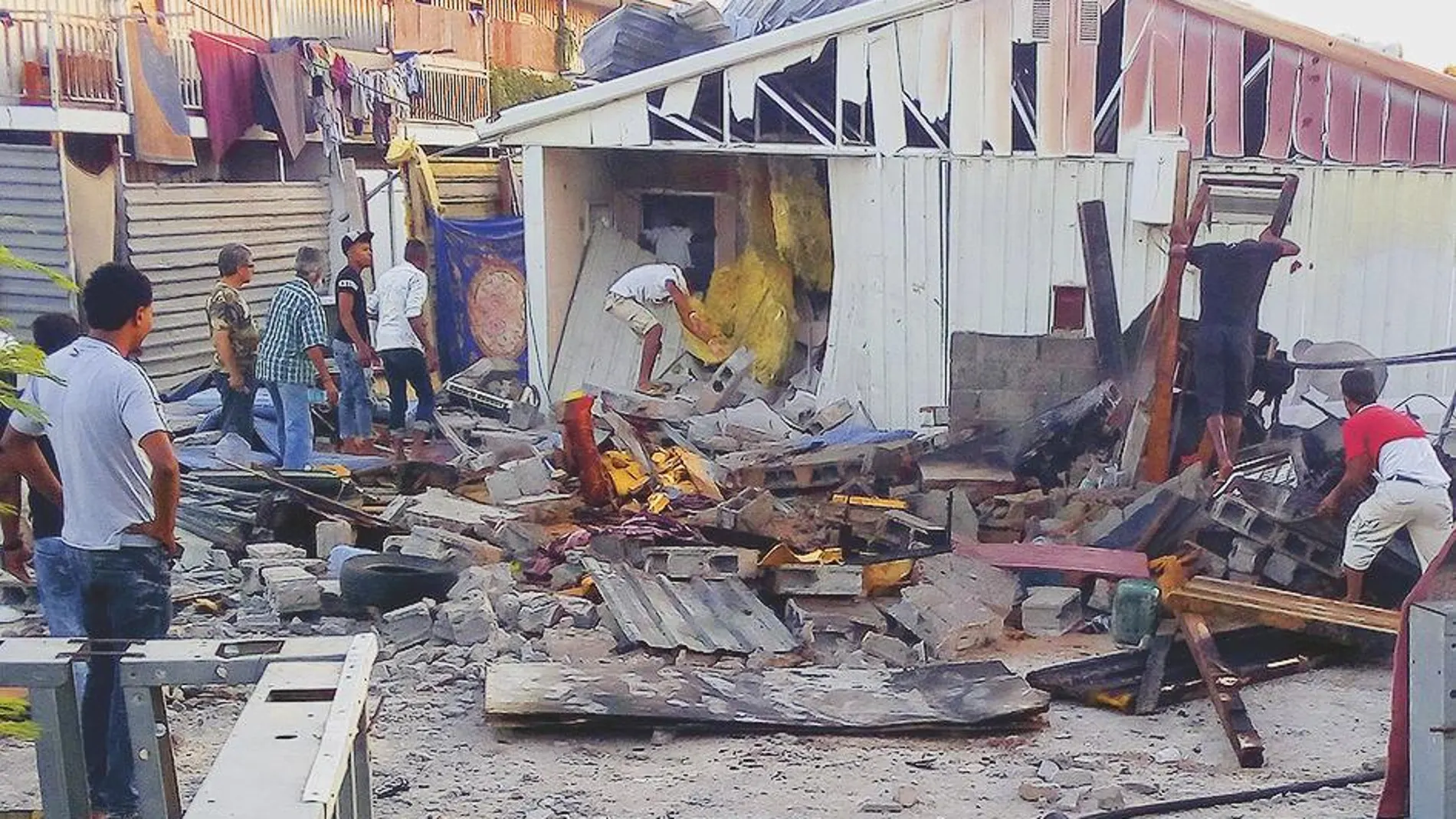 Varias personas comprueban los daños ocasionados por un cohete que impactó ayer en un campo de refugiados de Trípoli