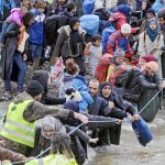 Los refugiados vadean un río en la frontera de Grecia con Macedonia