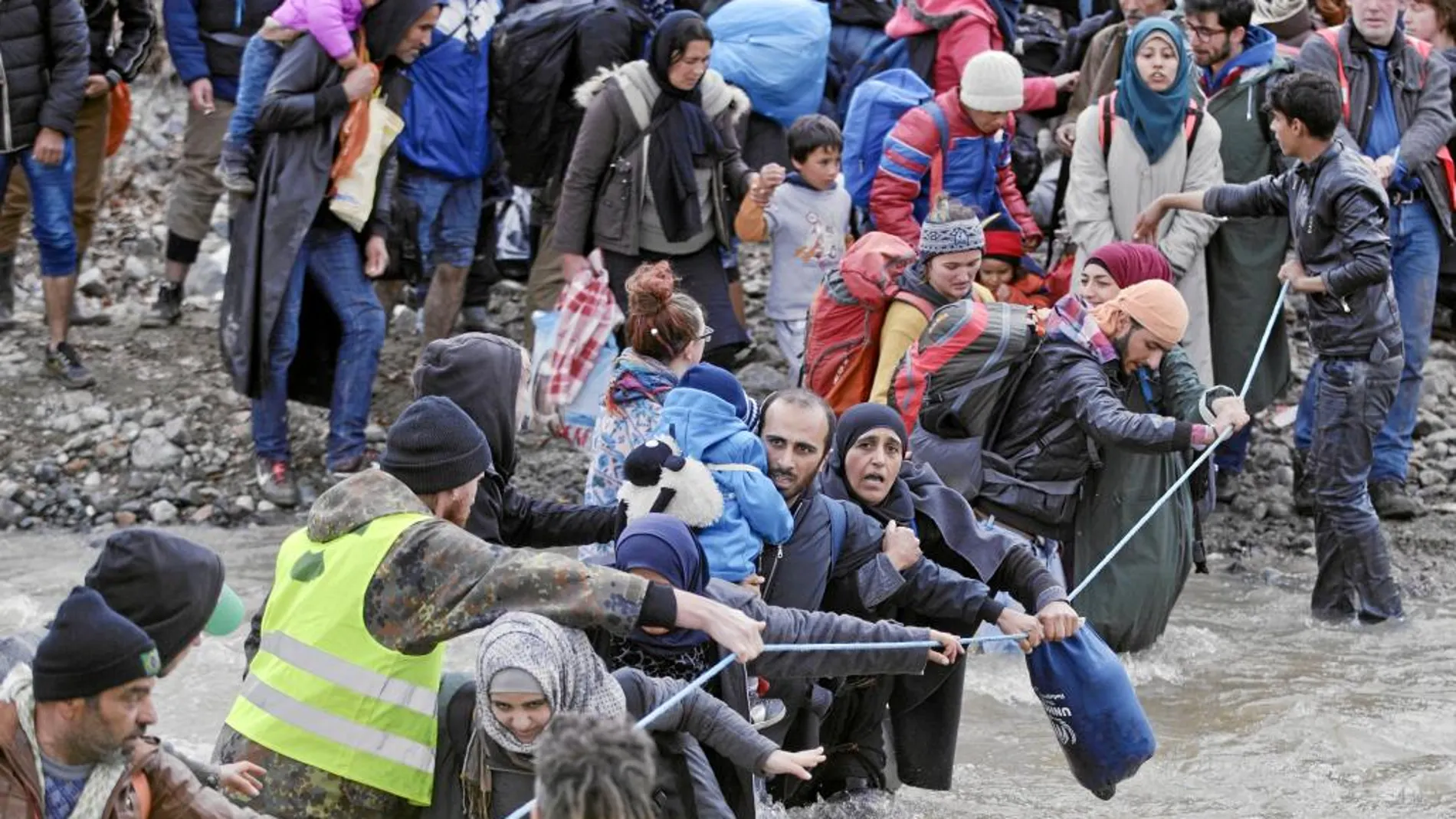 Los refugiados vadean un río en la frontera de Grecia con Macedonia