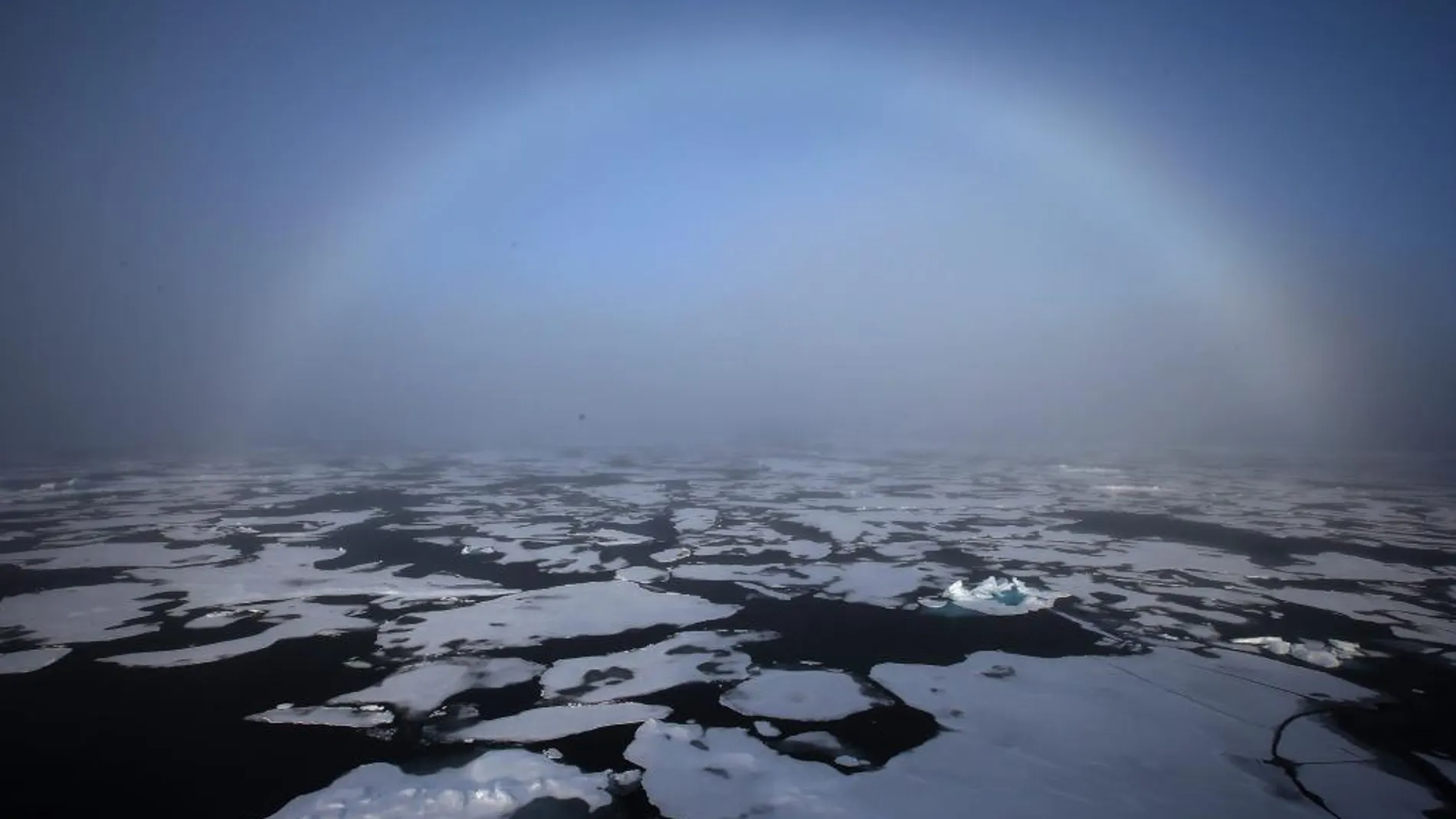 Un arco iris apareciendo en el horizonte en el Ártico