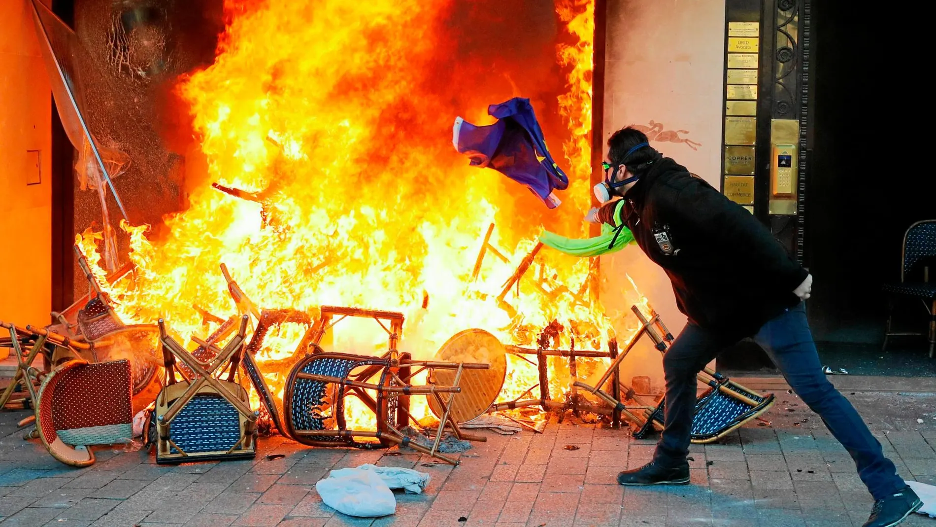Un «chaleco amarillo» lanza ayer una silla contra un establecimiento en llamas en la capital francesa