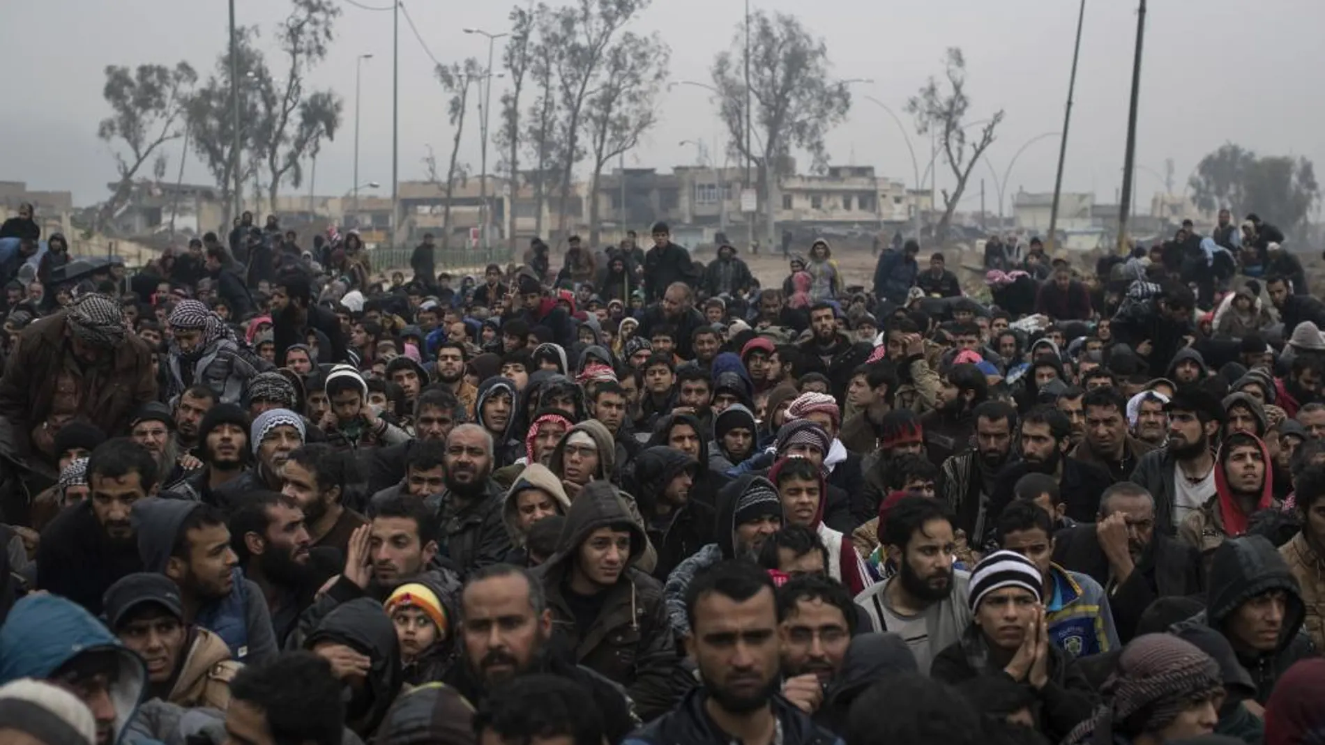 Desplazados iraquíes esperan antes de ser trasladados a un campamento en la parte occidental de Mosul