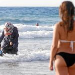 Una mujer musulmana ataviada con el hijab se baña en una playa con su hijo