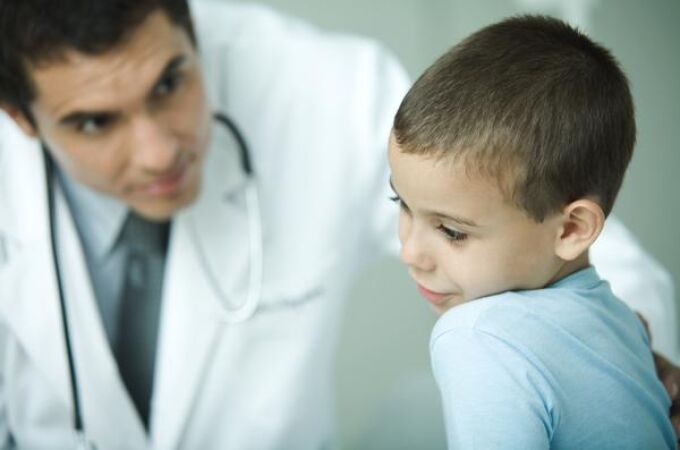 Un médico examina el oído de un niño en la consulta