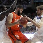 Los jugadores del Real Madrid Andrés Nocioni (d) y Othello hunter (i) intentan arrebatar el balón al pívot del Valencia Basket Bojan Dubljevic